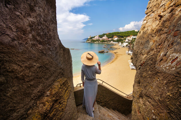 男人一个戴帽子的女孩站在山坡上 俯瞰着意大利的大海和海滩景观客厅享受假期