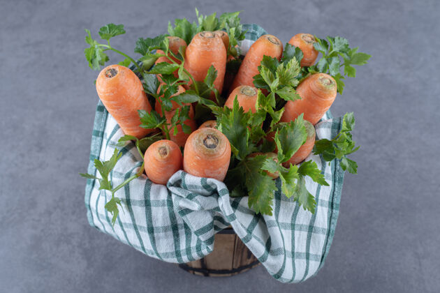 胡萝卜胡萝卜和叶子放在毛巾上的桶里 放在大理石的表面上美味生的美味