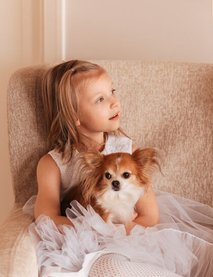 童年一个穿着漂亮白裙子的可爱小女孩抱着一只小狗吉娃娃家庭肖像天使