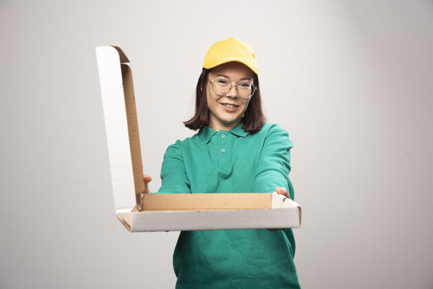 年轻人女送货员在一张高质量的白色照片上给一纸板比萨饼女士女人眼镜