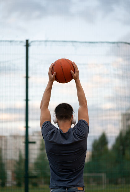 年轻一个男人背对着运动场站着 手里拿着一个篮球技能活跃人