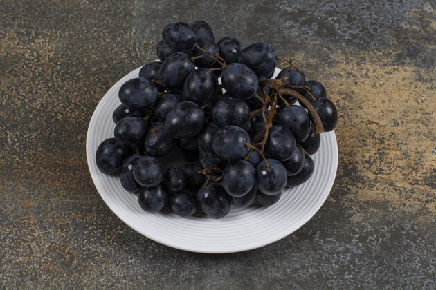 食品白色盘子上的一簇黑葡萄美味自然农业