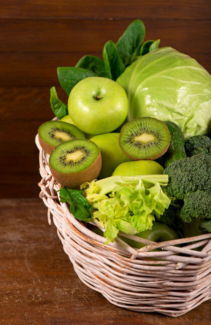 黄瓜绿色蔬菜-猕猴桃 卷心菜 香草 芹菜 西兰花 黄瓜在一个木制的篮子背景沙拉厨房生的