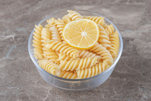 美味一片柠檬放在碗里的意大利面上 放在大理石表面上美味碗碳水化合物