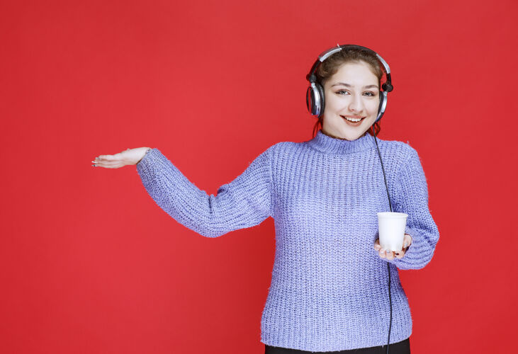 音乐戴着耳机拿着一次性咖啡的女孩人类休闲女性