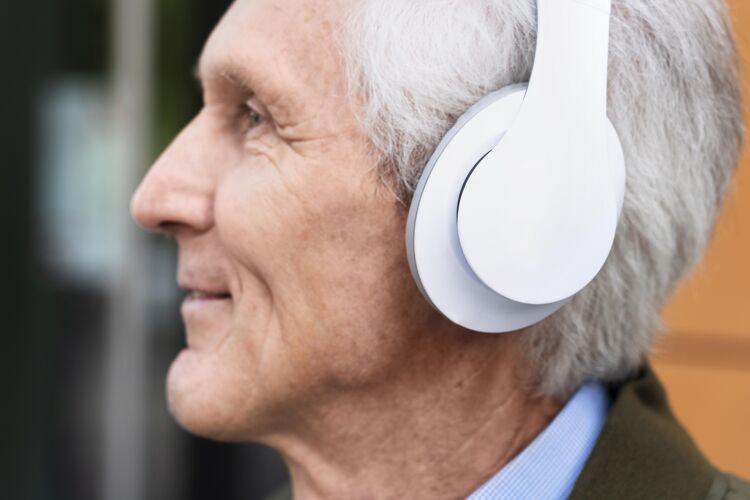 城市笑眯眯的城里老人戴着耳机听音乐男人耳机退休