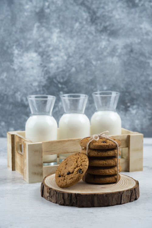 牛奶三杯牛奶和一堆饼干放在大理石桌上木头面包房绳子