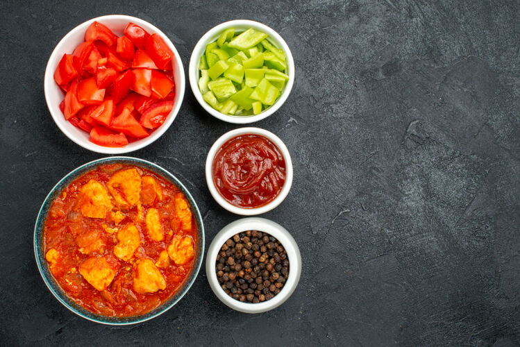 西红柿俯瞰美味的鸡肉片与番茄酱和新鲜蔬菜的深色背景鸡肉酱菜番茄肉胡椒碗观点
