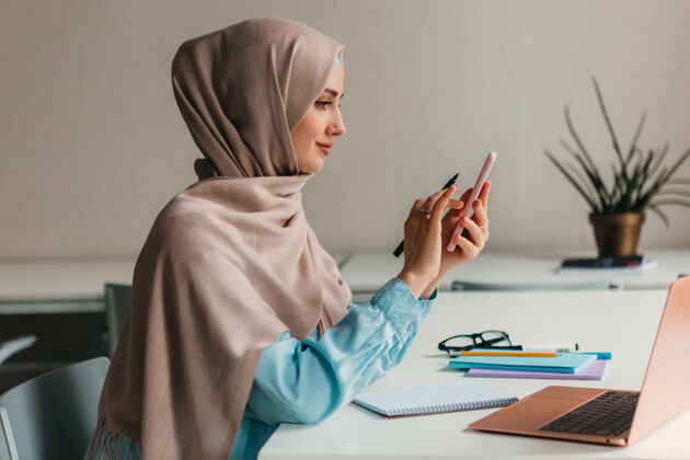 工作年轻漂亮的现代穆斯林妇女戴着头巾在办公室的笔记本电脑上工作 教育在线时尚围巾工作场所
