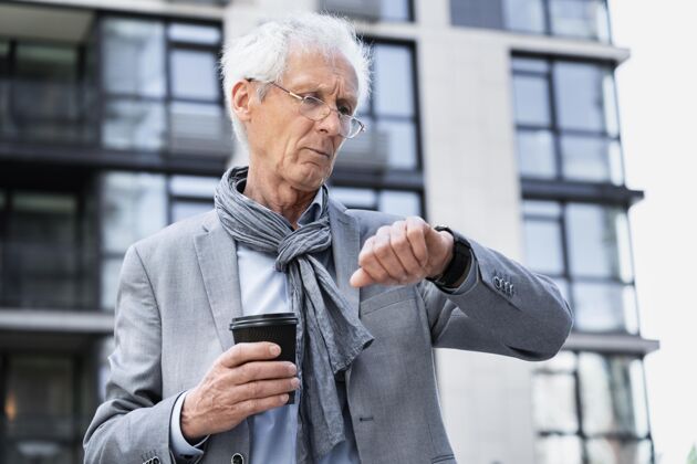 成熟时尚的老男人在城里看智能手表城市老年人男人