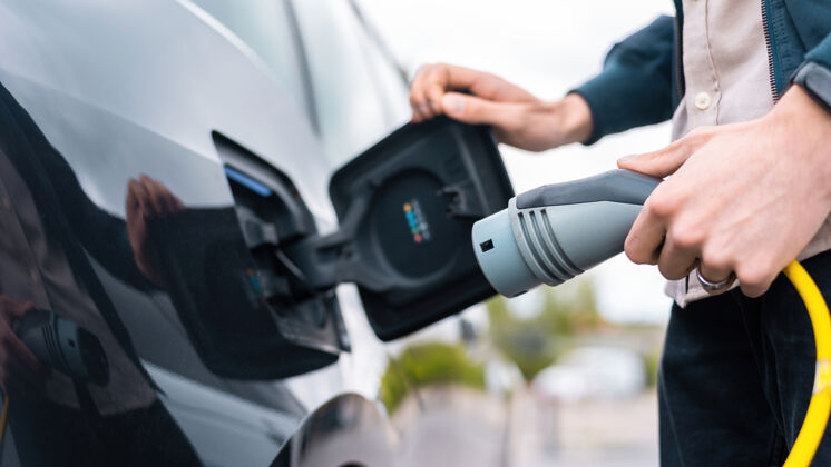 汽车男子打开汽车充电插座和手持充电器在充电站未来车辆充电器