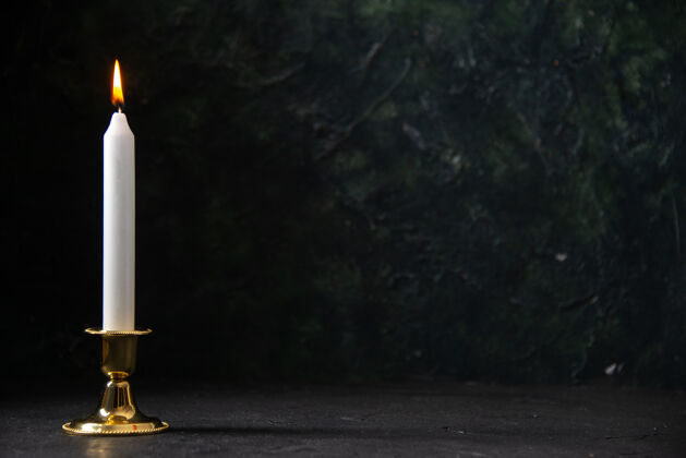黑夜在黑色的金色的立场上白色蜡烛的正面视图黑暗葬礼灯塔