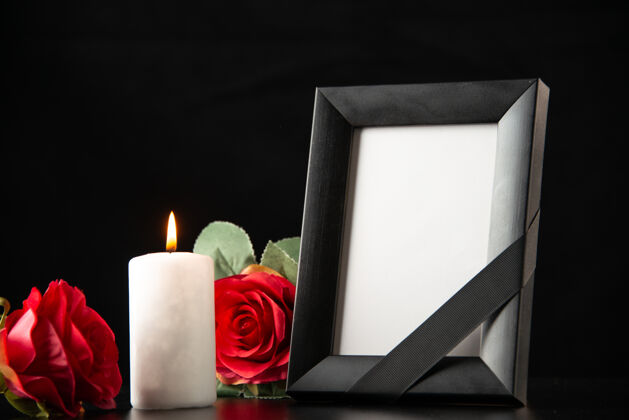 庆典黑暗中有蜡烛和红花的相框的前视图光死亡相框