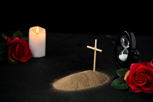 蜡烛小墓穴的正面图 黑色上有蜡烛和红玫瑰火葬礼打蜡