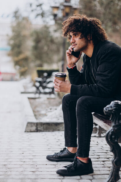 埃及卷发的年轻人一边喝咖啡一边打电话科技时髦喝酒