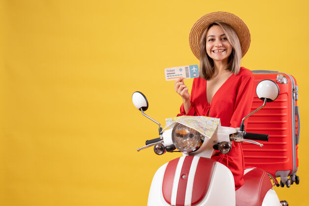 旅行者正面图：坐在轻便摩托车上的年轻女士拿着红色的手提箱举着车票度假成人向上