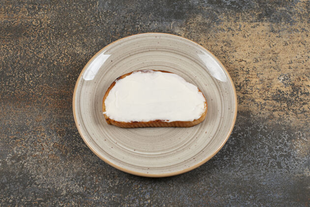 吐司在陶瓷盘子上放一片烤面包和酸奶油酸奶油面包涂抹