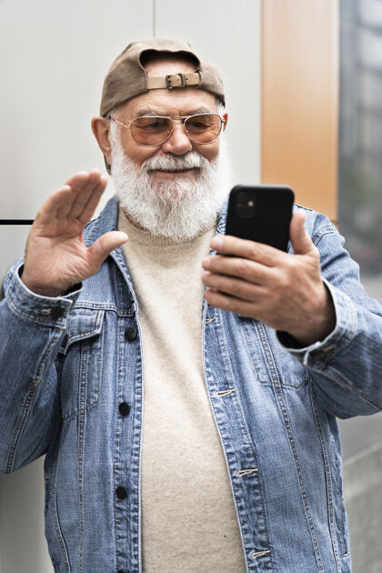 老年在城市户外用智能手机打视频电话的老人退休视频通话男性