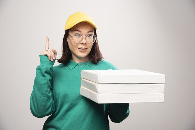 纸箱女送货员竖起大拇指 拿着一张白色的高质量照片上的比萨饼卡片女性年轻人盒子