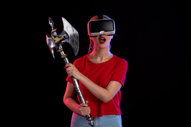 女性美丽的女性在黑暗中玩虚拟现实的前视图游戏女孩肖像