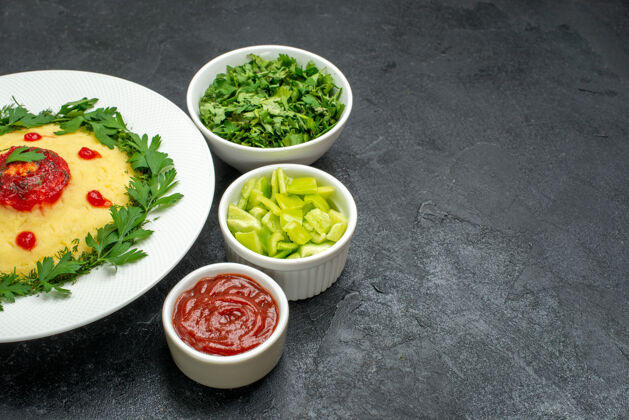 碗前方是黑暗空间里的土豆泥 配番茄酱和绿色蔬菜晚餐生菜晚餐
