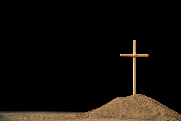 黑色黑暗中带十字架的小坟墓的正视图墓地沙子十字架