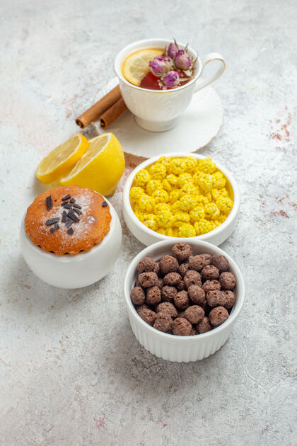早餐前视图一杯茶与糖果和柠檬片上的白色空间茶前面水果