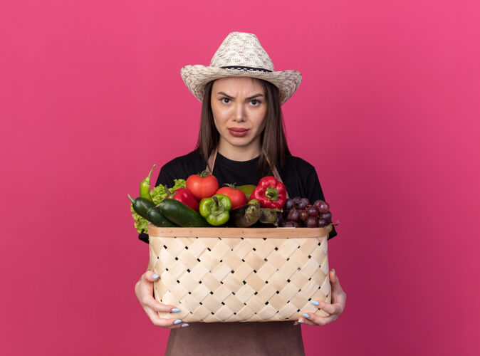 粉红愤怒漂亮的白人女园丁戴着园艺帽拿着菜篮子抱花园漂亮