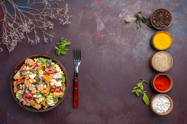 菜肴俯瞰美味的蔬菜沙拉与不同的调味品在黑暗的地板上健康饮食蔬菜沙拉午餐饮食托盘容器