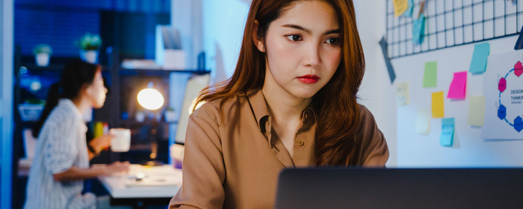日语快乐亚洲女商人社交距离在新的正常情况下病毒预防 同时使用笔记本电脑在线业务加班回到办公室晚上成人女性迟到