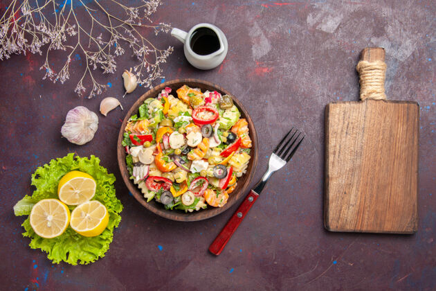 平底锅俯瞰美味的蔬菜沙拉配柠檬片和绿色沙拉的深色背景餐健康饮食沙拉盘子晚餐美食