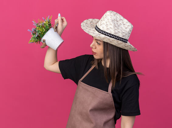 花园漂亮的白人女园丁戴着园艺帽捧着花盆看花儿帽子请举行