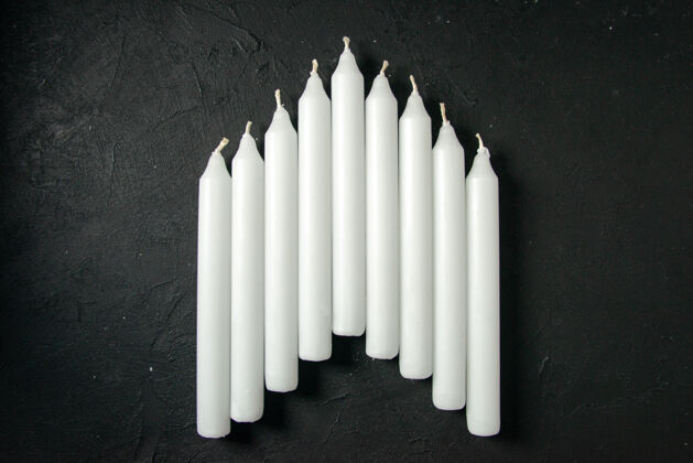 黑暗黑墙上白色蜡烛的顶视图画木头顶