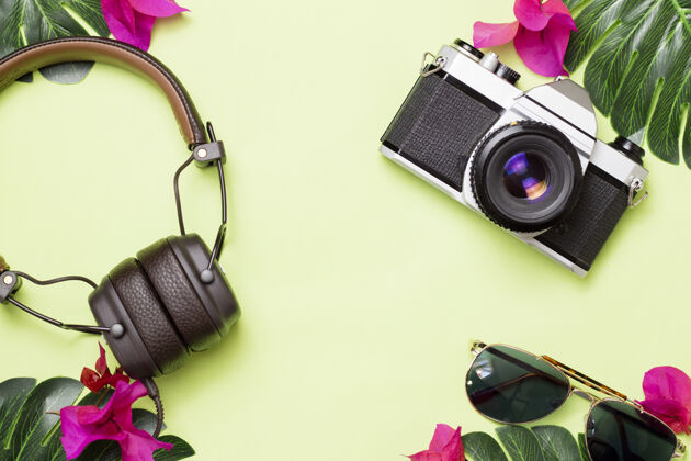 海滩复古相机 耳机和热带花卉眼镜绿色表面桌子花设备
