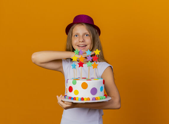 女孩漂亮的小女孩戴着节日帽 手里拿着生日蛋糕开心又兴奋 生日派对概念聚会兴奋举行