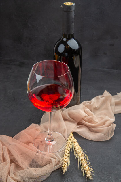 葡萄酒正面近距离观看红酒在毛巾上的玻璃高脚杯和黑色背景上的瓶子庆典酒杯酒杯
