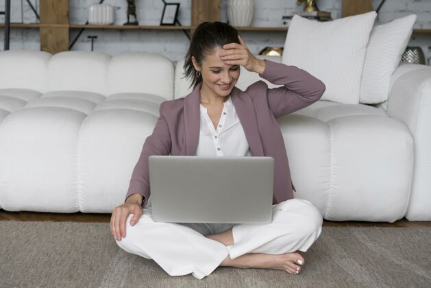 科技坐在地板上膝上放着笔记本电脑的女人设备房子通讯