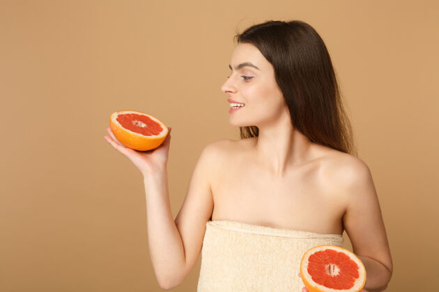 提升近景半裸体女人完美的皮肤裸妆举行葡萄柚隔离米色粉彩墙上纯净室内护理
