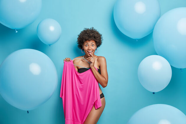积极女人半裸着内衣摆姿势 衣架上挂着粉色的裙子 蓝色的摆姿势女士服装气球