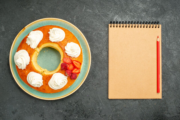 食物俯视图美味的圆形馅饼配水果和奶油在深色背景上茶糖饼干饼干蛋糕甜板水果杯子