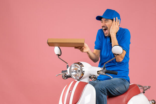 摩托车前视图的信使男子戴着帽子坐在滑板车上头痛的粉彩桃背景自行车背景痛苦