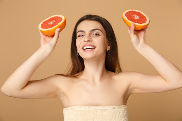 毛巾近景半裸体女人完美的皮肤裸妆举行葡萄柚隔离米色粉彩墙上头发健康姿势
