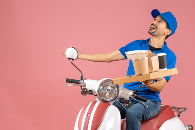 桃顶视图快乐的情感信使男子戴着帽子坐在粉彩桃色背景上踏板车人粉彩人