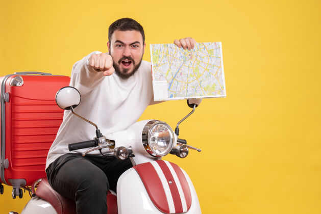 成人顶视图野心勃勃的年轻人坐在摩托车上 手提箱上拿着地图 背景是孤立的黄色摩托车人物男性