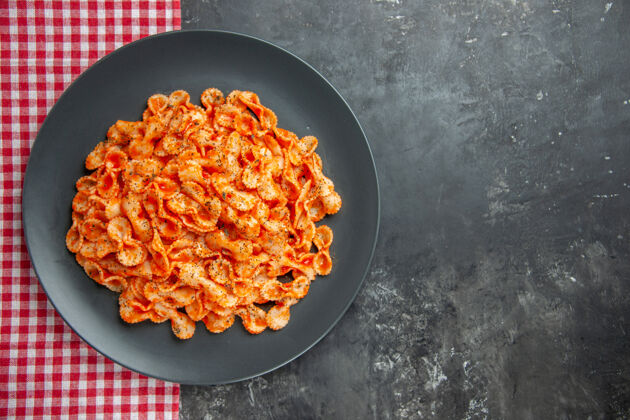 毛巾在黑暗背景下 在一个黑色的盘子里 用一条红色的毛巾 近距离观看美味的意大利面食胡萝卜深色午餐