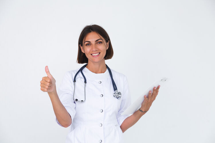 工作女医生穿着白大褂 自信地微笑着拿着白纸空白竖起大拇指十字架信心治疗师