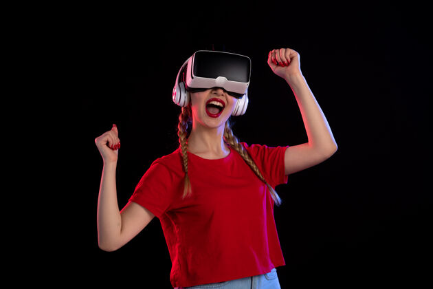 视图年轻女性戴着耳机在黑暗的墙上玩虚拟现实的前视图游戏耳机人物