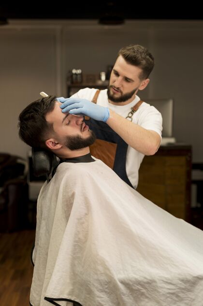 职业理发师剃须和轮廓男客户的胡须雇员理发师男人