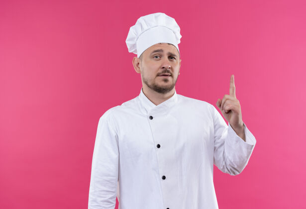 厨师自信的年轻帅哥厨师身着厨师制服 孤零零地站在粉红色的墙上帅气自信年轻