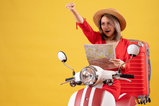 坐着穿着红裙子的漂亮女孩 骑着轻便摩托车 提着大箱子 拿着地图车辆摩托车漂亮女孩